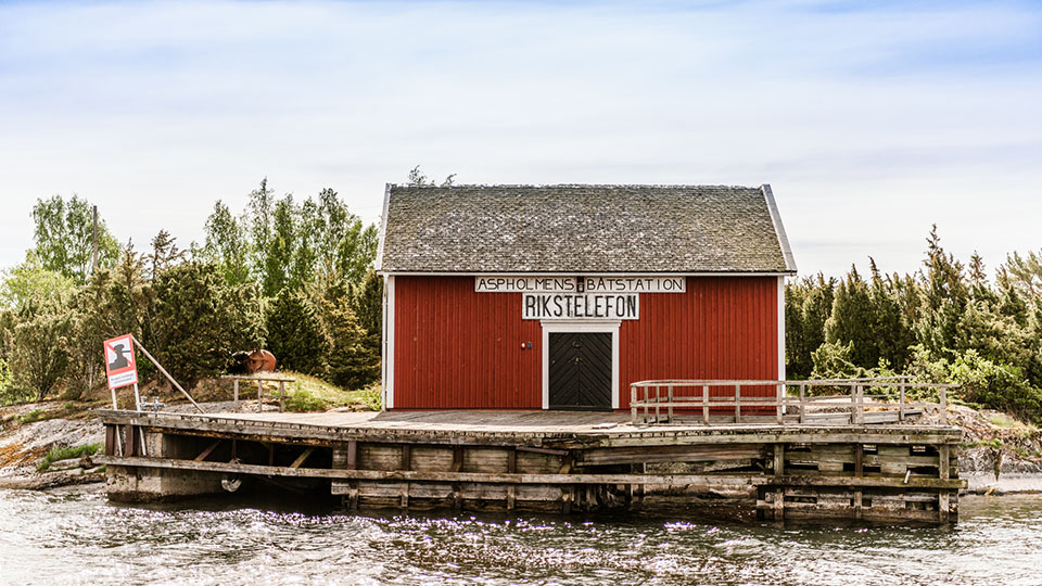 Ön Aspholmen med naturhamn är ett av många smultronställen i Lurö skärgård. Här i det röda huset fanns det förr telefon, skylten för Rikstelefon sitter fortfarande kvar på huset. 