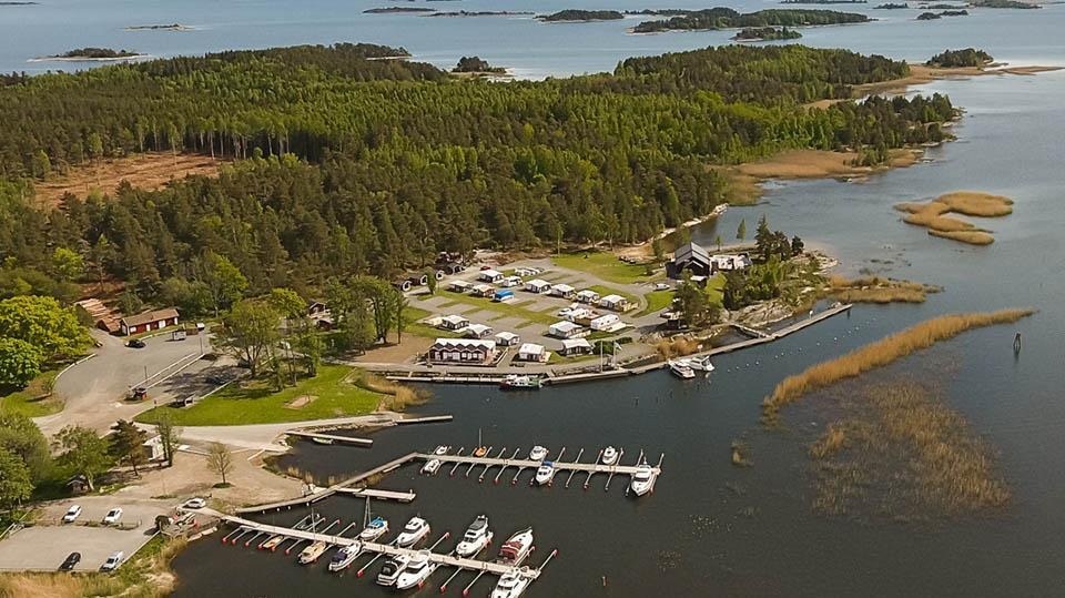Flygfotot över Ekenäs över gästhamn med campingen, restaurang och gästhamnsbryggan. Längst ut breder Vänern ut sig och man kan se öar i Eskilsäters skärgård. 