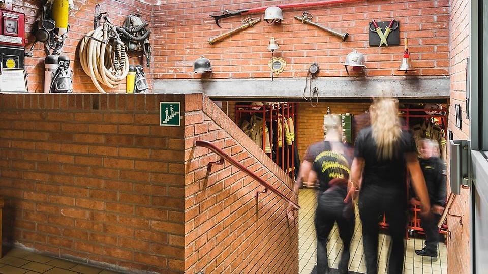 Två medarbetare från Säffle räddningstjänst går nedför en trappa i Säffle brandstation