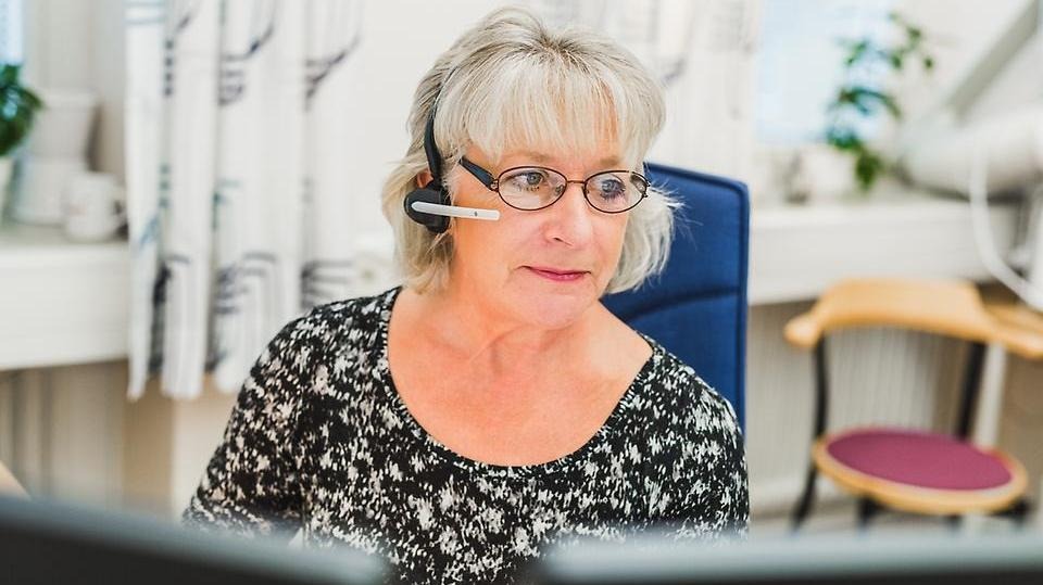 Kvinnlig medarbetare i Säffle kommun talar i telefon med headset