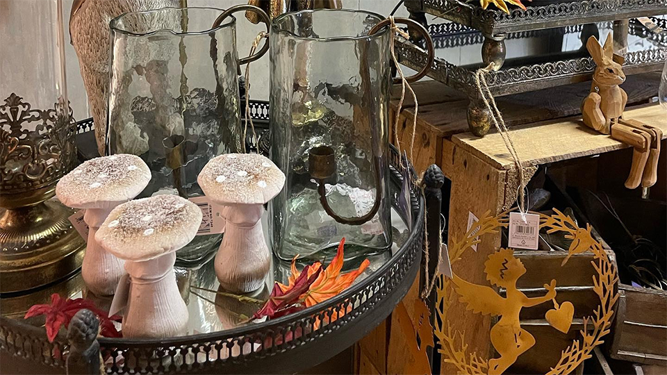 Bilden visar ett litet bord med många dekorativa inredningsdetaljer och bruksföremål som kannor i glas hos Vackert Hemma.