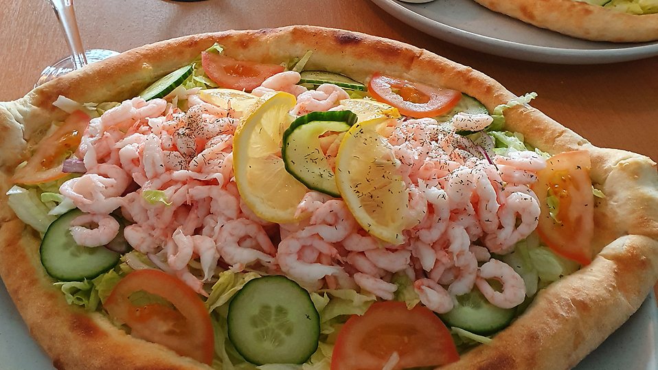 Pizzan är serverad på Svanskog Pizzeria Gyllene Svanen. På bild ses "Mor i skutan", en bland flera utsökta pizzor och maträtter som finns på menyn. Se till att boka plats och deg, besökare åker långväga för den goda matens skull. 